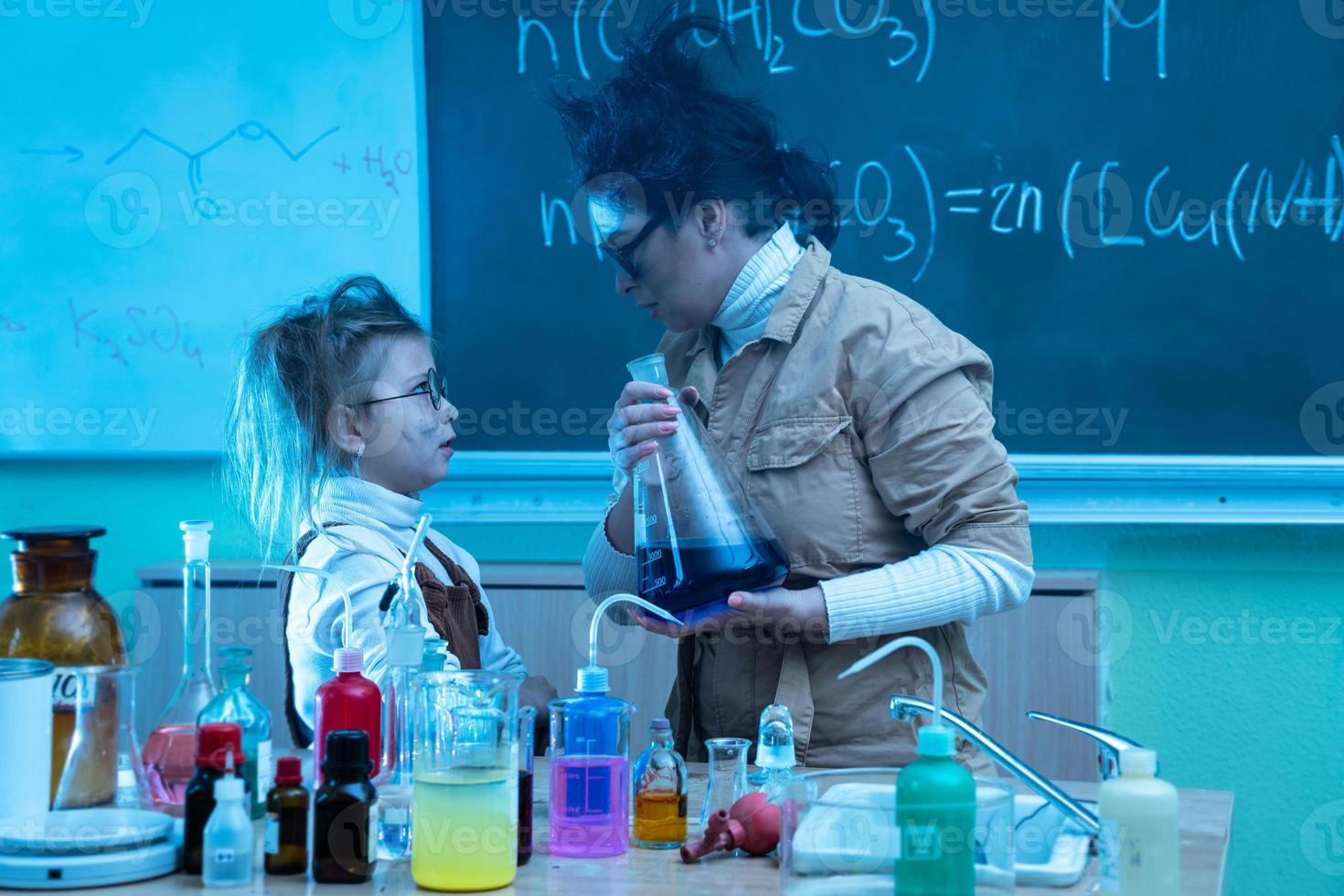 profesor y niña durante la lección de química mezclando productos químicos en un laboratorio foto