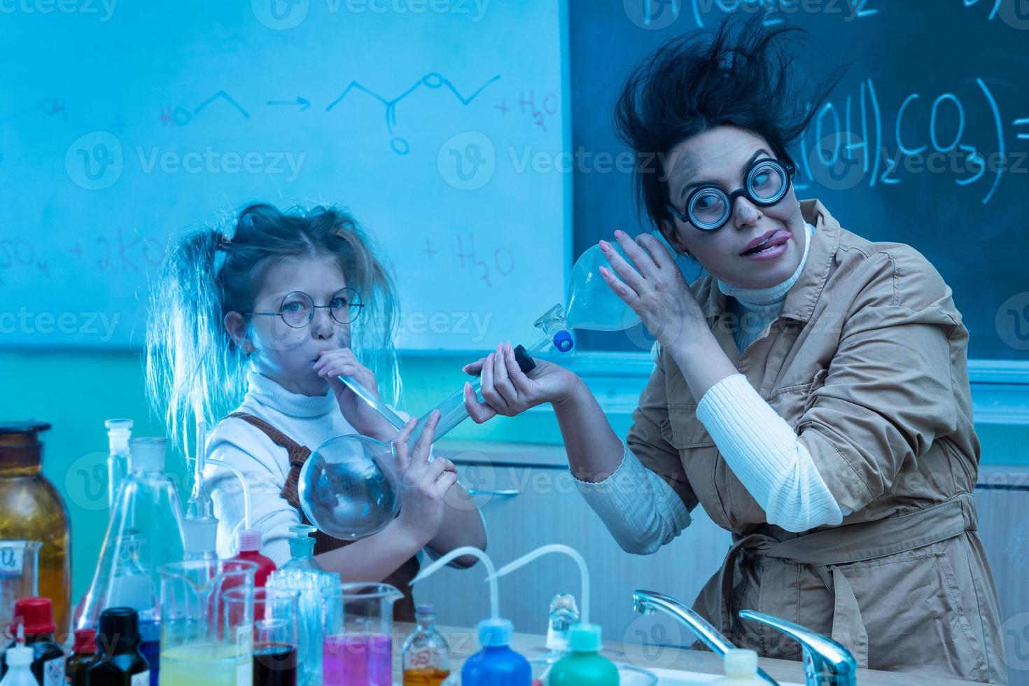 Teacher and little girl during chemistry lesson mixing chemicals in a