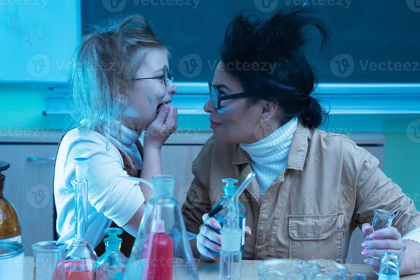Teacher and little girl during chemistry lesson mixing chemicals in a laboratory photo