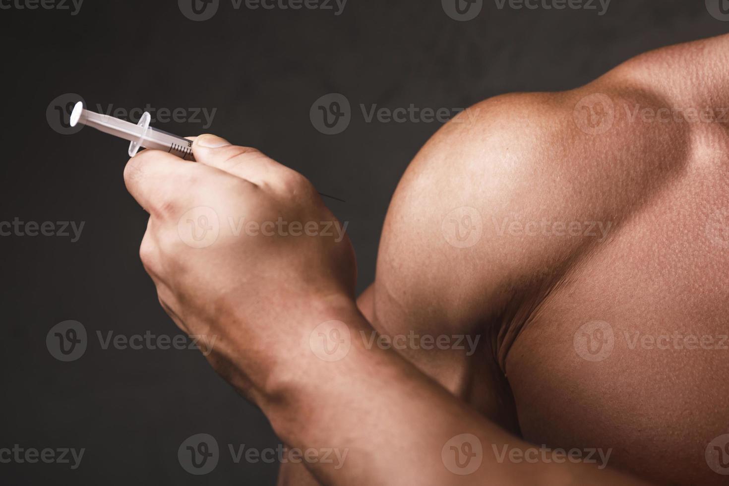 Muscular man with a syringe in his hand photo