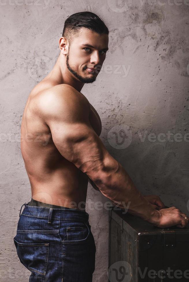 Massive bodybuilder posing beside the concrete wall photo