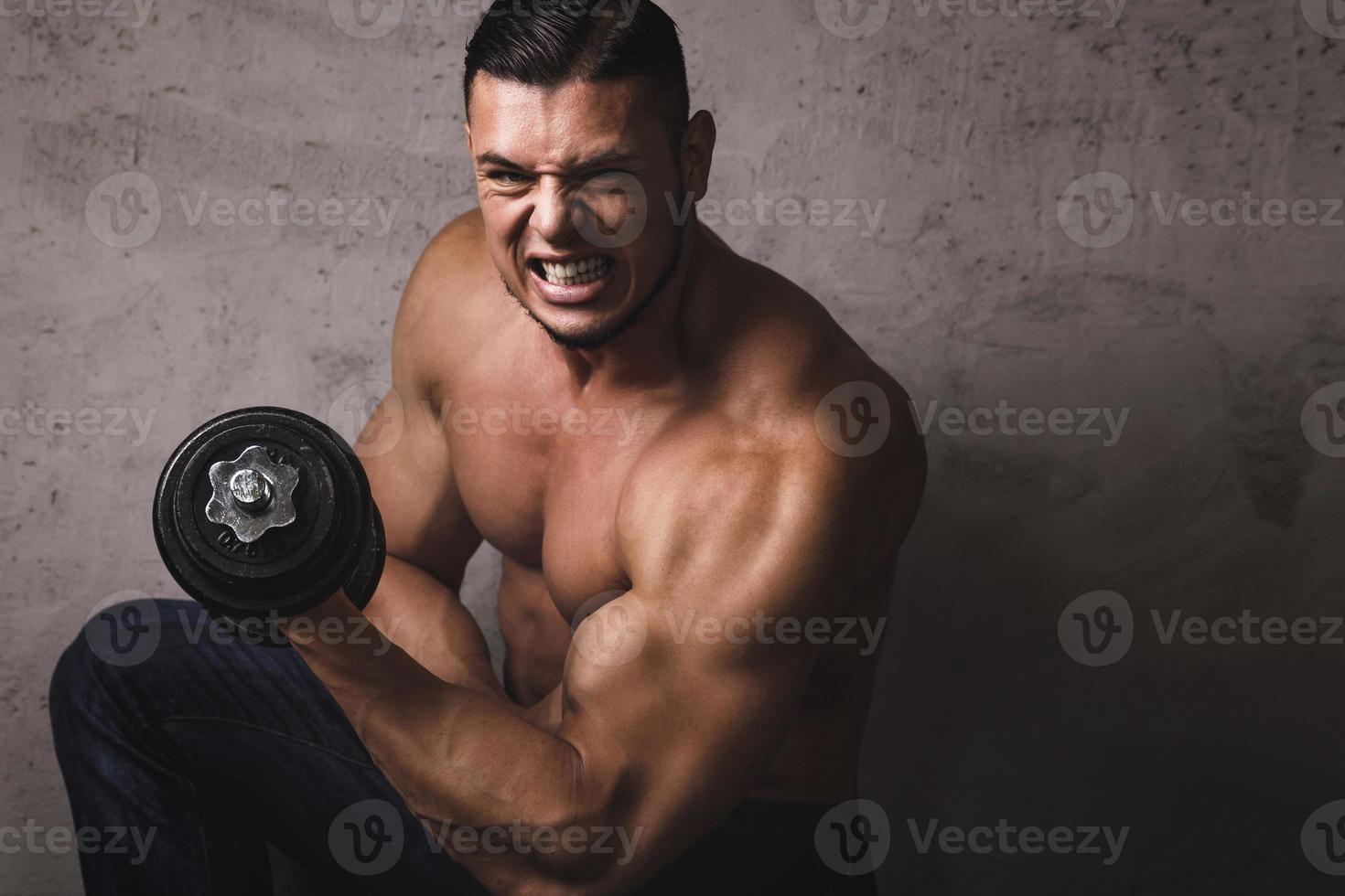 Massive bodybuilder doing biceps curl exercise with the dumbbell photo