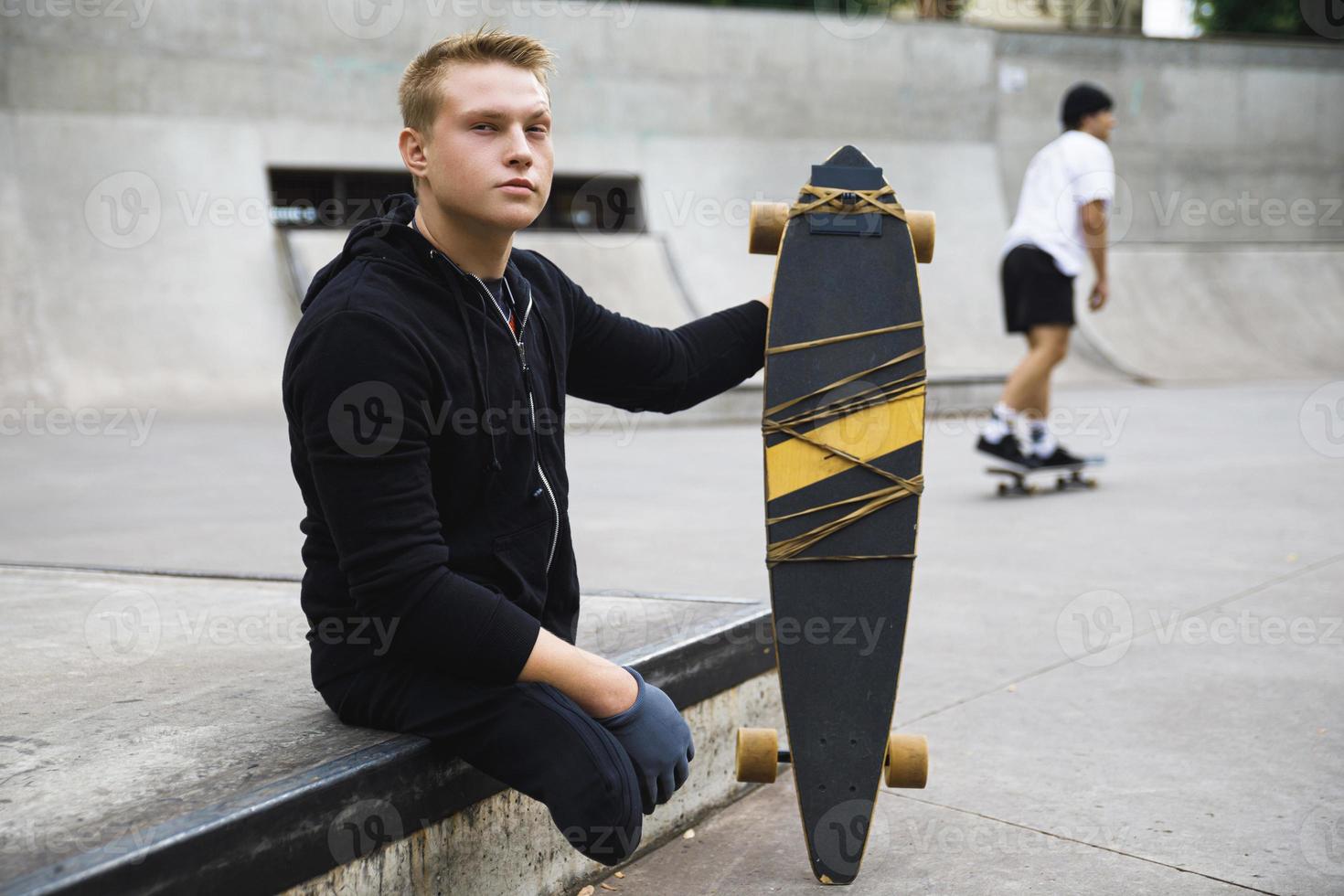 chico discapacitado motivado con un longboard en el skatepark foto