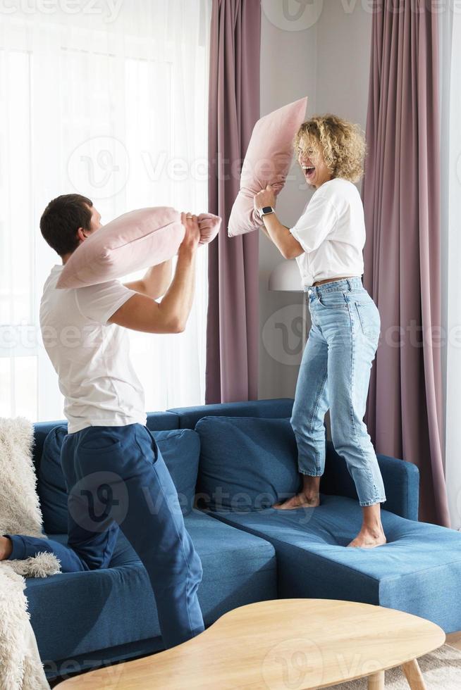 Happy couple during the pillow fight in their apartment photo