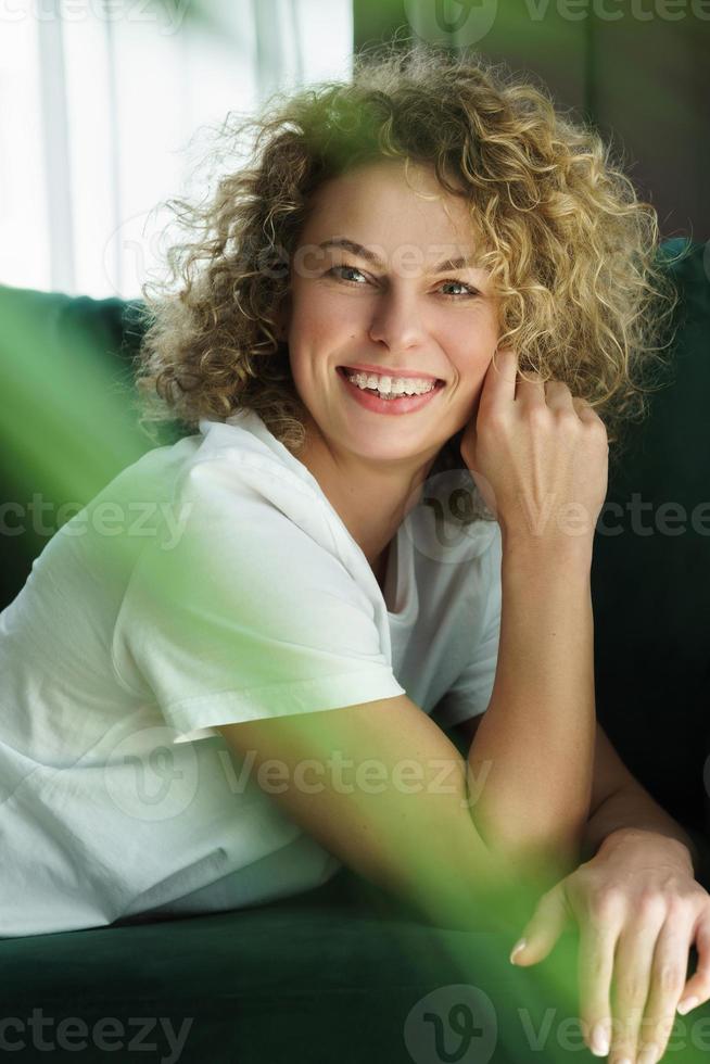 bella mujer con el pelo rizado tumbado en un sofá verde foto