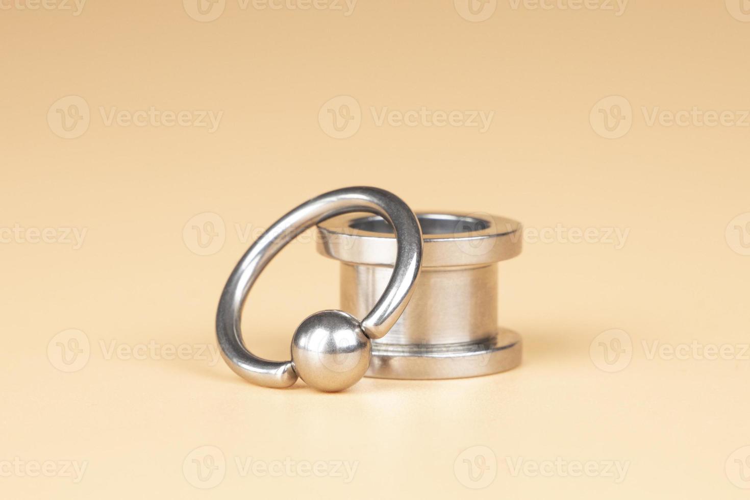 silver tunnel piercing accessory close up on beige background 16242950 Stock Photo at Vecteezy