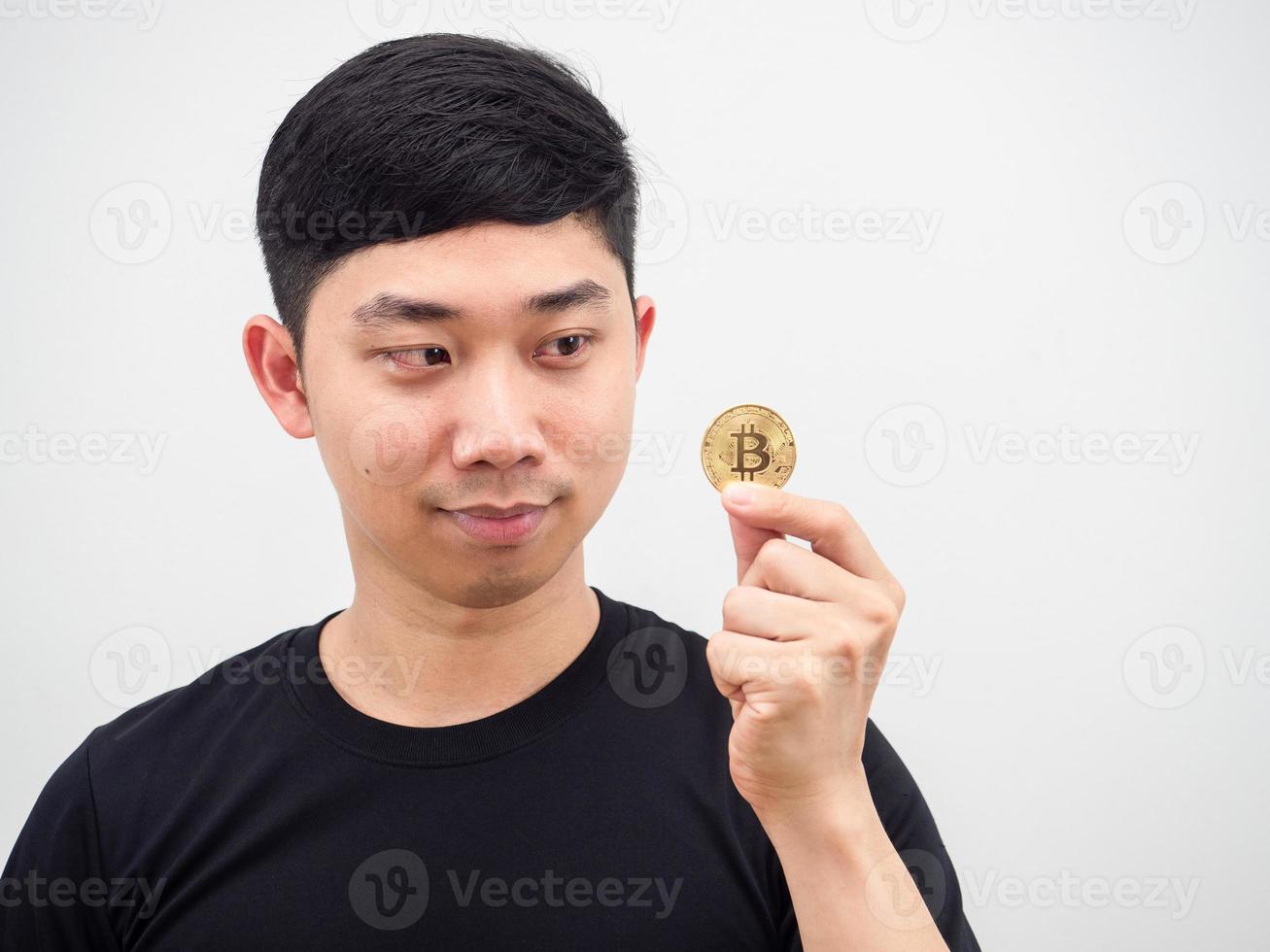 hombre asiático de primer plano mirando bitcoin en su mano y cara de sonrisa sobre fondo blanco foto