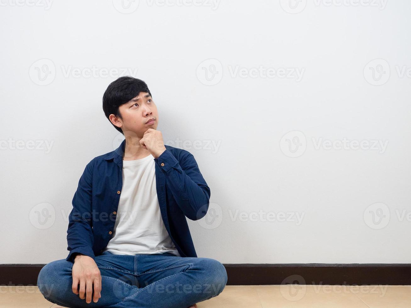 Asian man sit on floor thinking and looking at copy space photo