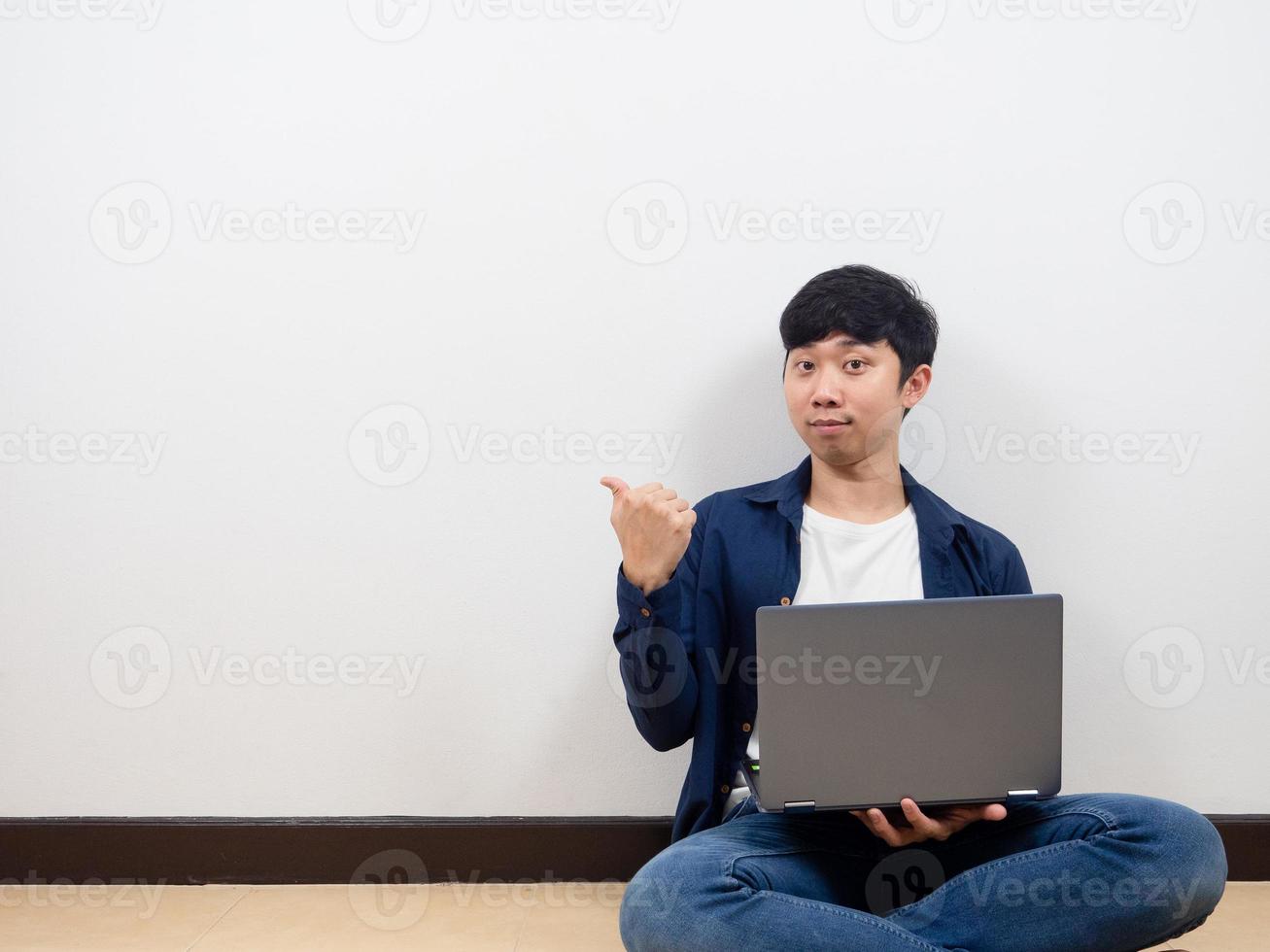 Man sit on floor with laptop and pint finger at copy space photo