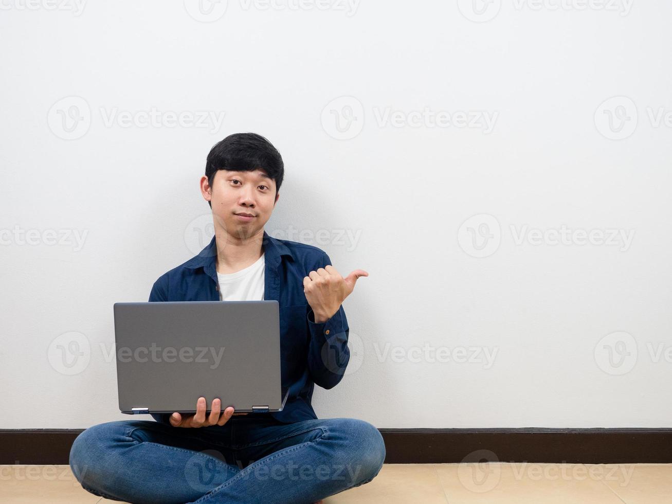 Man sit on floor with laptop and pint finger at copy space white background photo