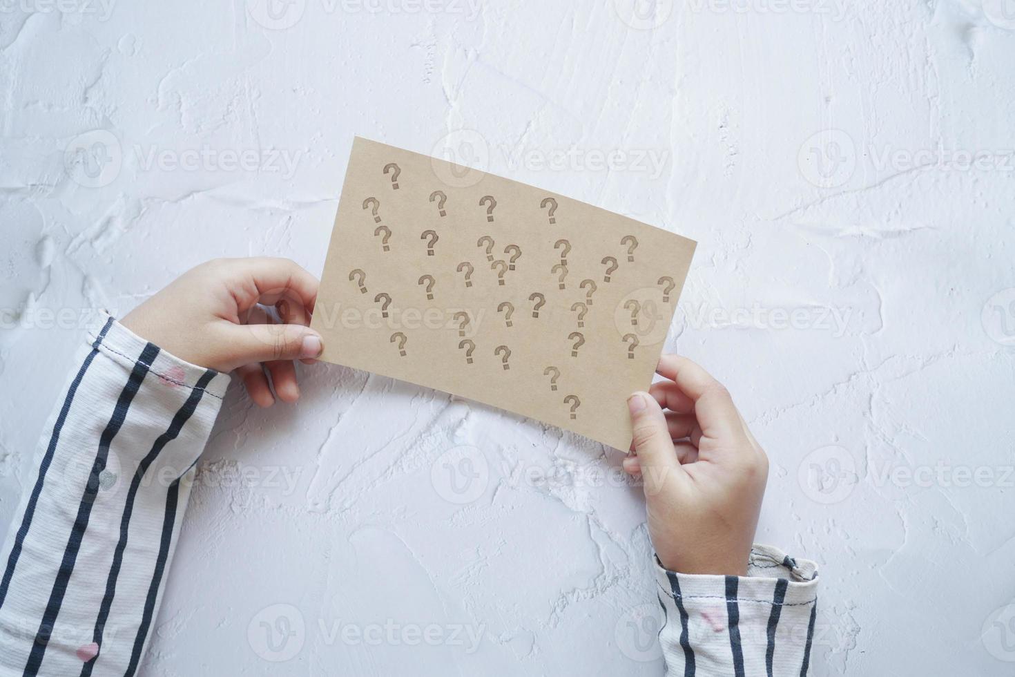 child holding a question mark paper on white background photo