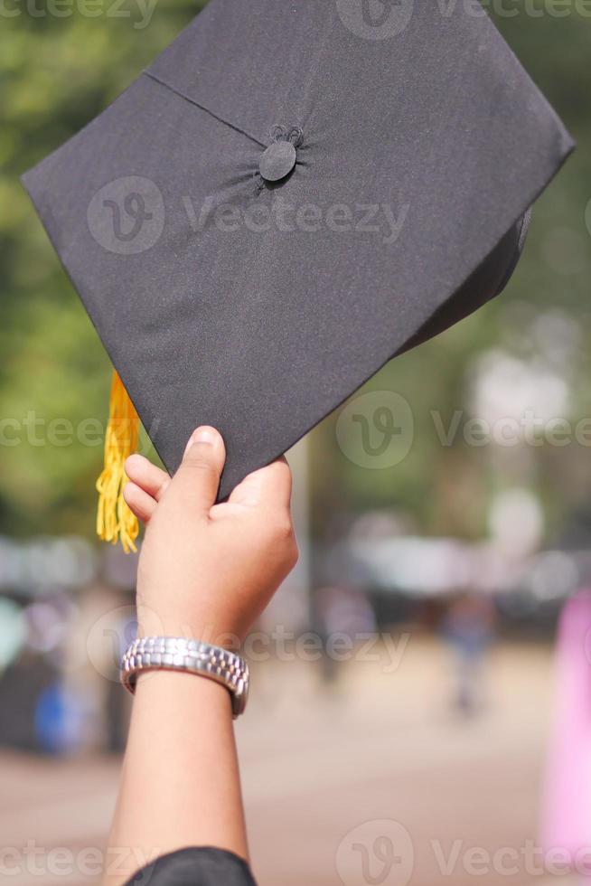 estudiante sostenga sombreros en la mano durante el éxito del comienzo con fondo amarillo foto