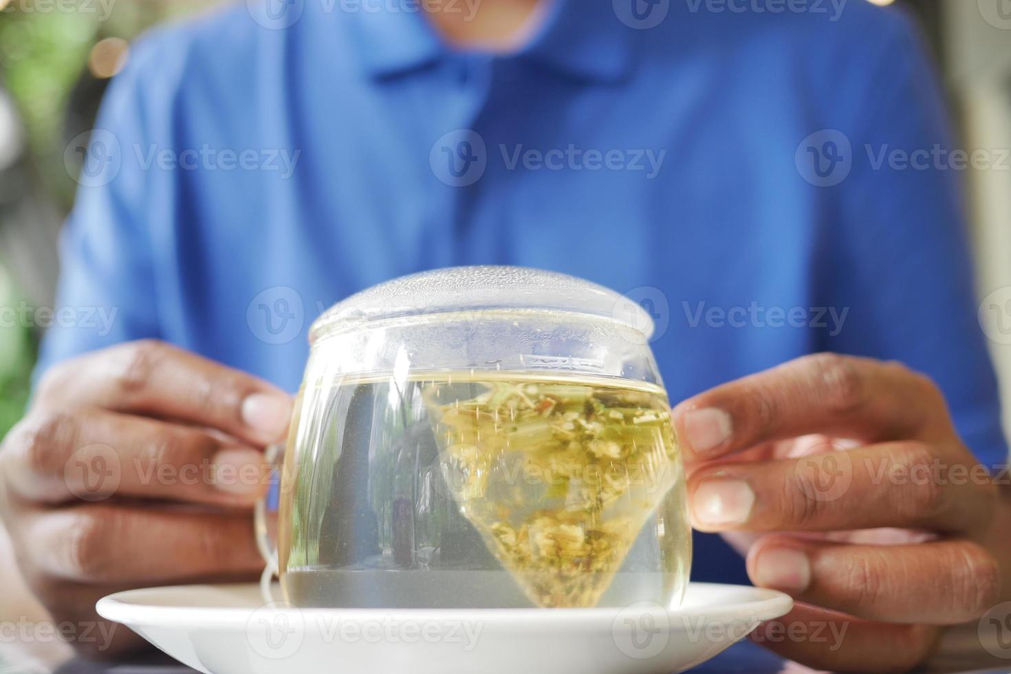 young men holding a cup of green tea and tea bag on table, photo