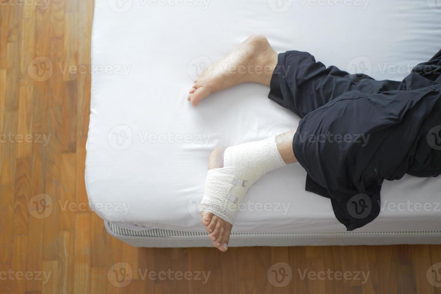 Woman with bandaged foot on bed top view photo