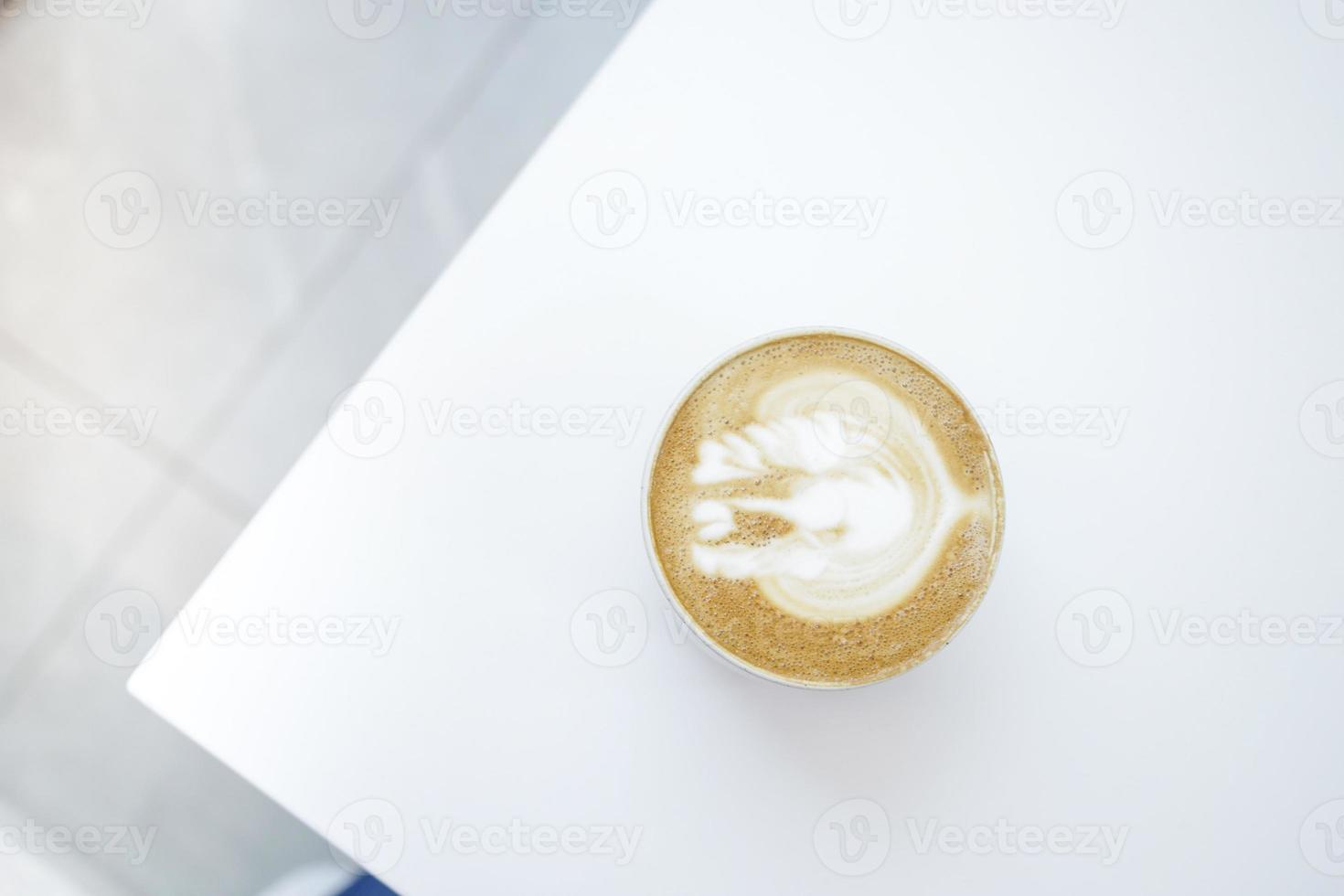 a cup of late coffee with flower shape design on top at cafe photo