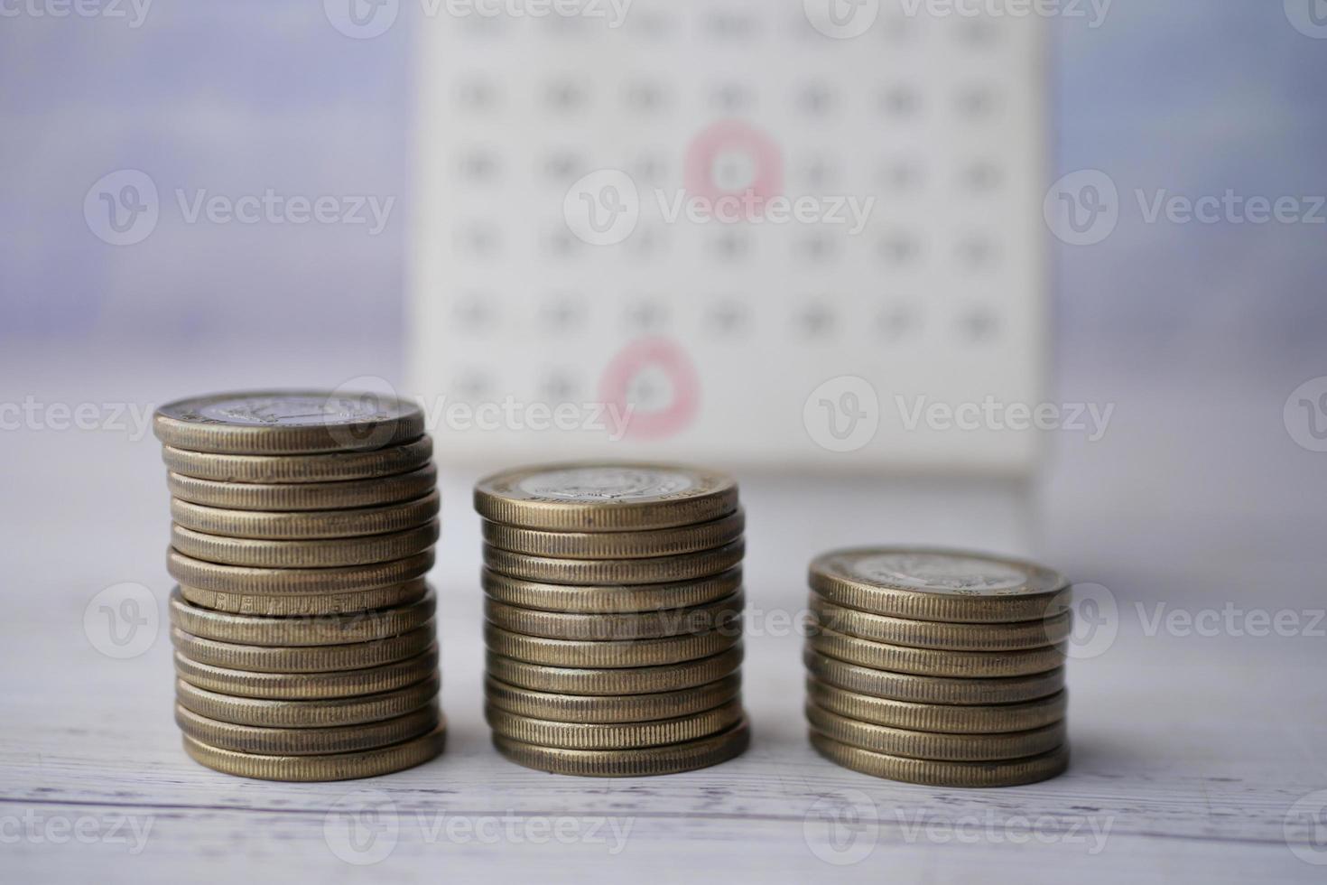 stack of coins and calendar on table photo