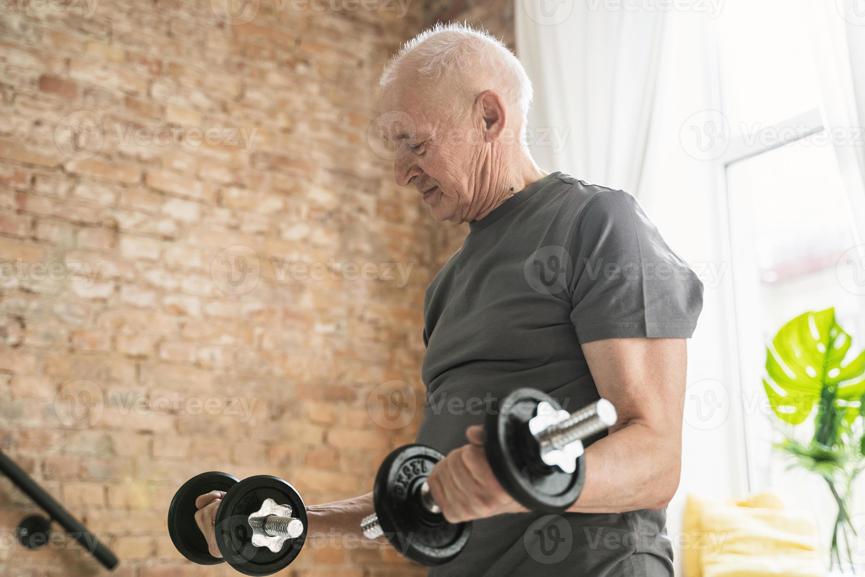 Elderly man exercising with a dumbbells during his workout in home