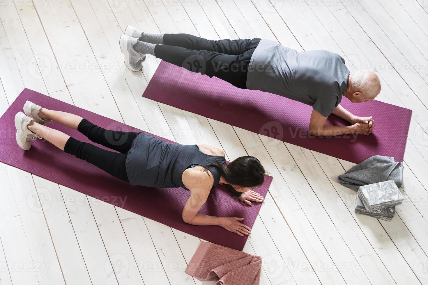 Active elderly people working out on the exercise mats at home photo