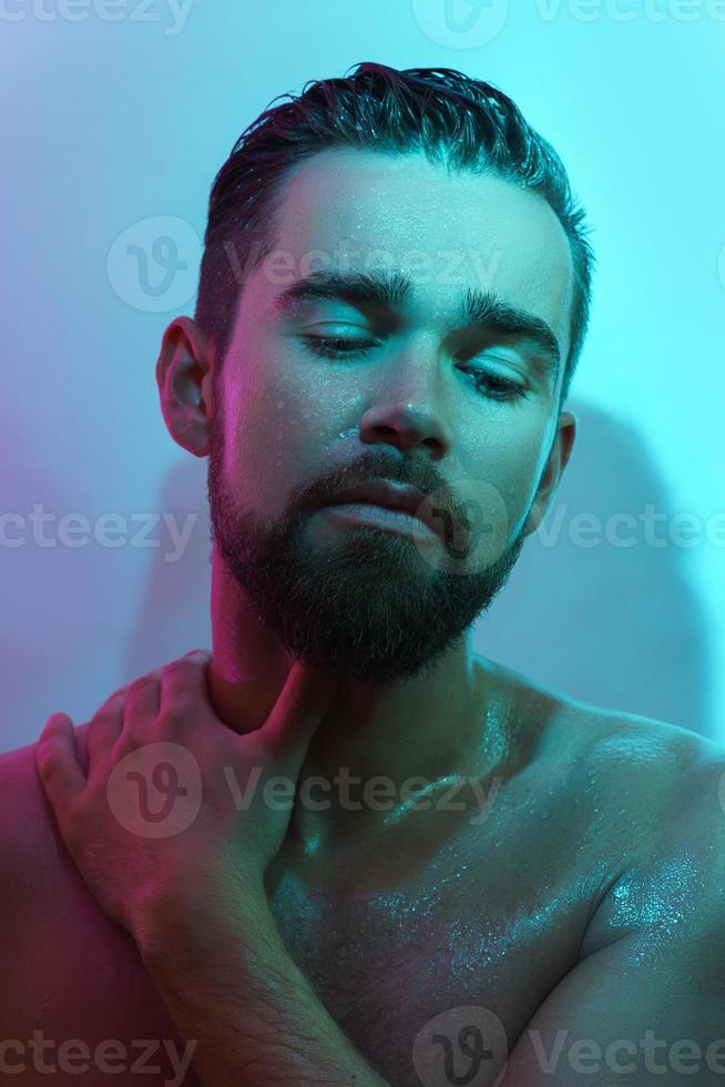 Handsome young man with wet skin in neon light photo