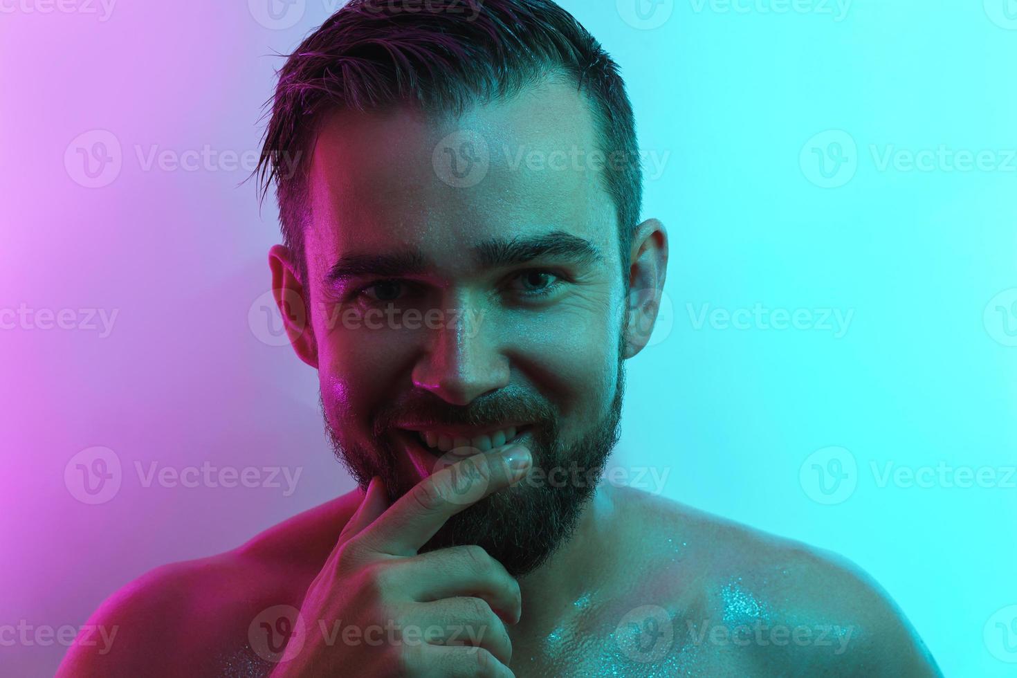 Handsome young man with wet skin in neon light photo