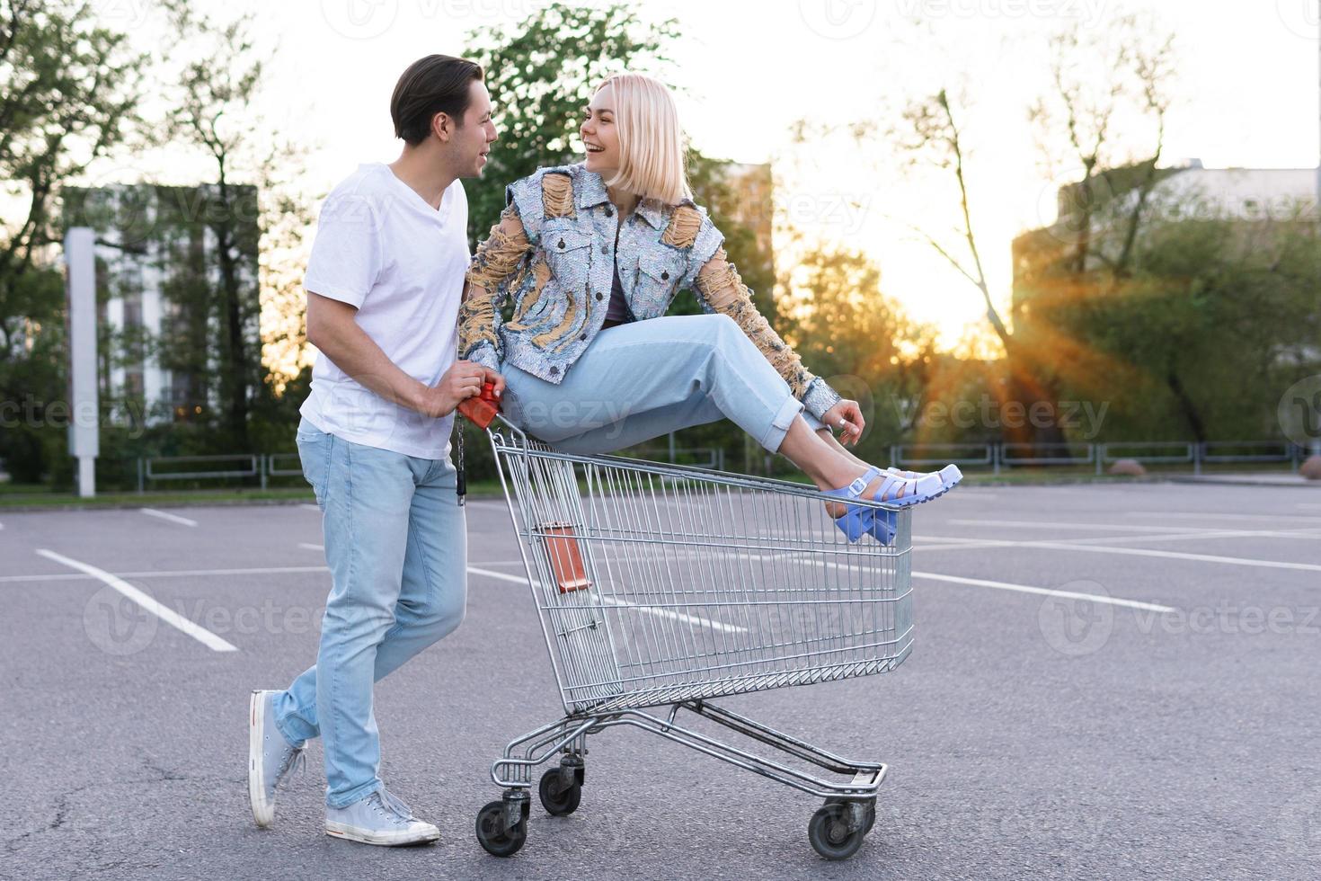 Young couple have fun with a shopping trolley on a supermarket parking photo