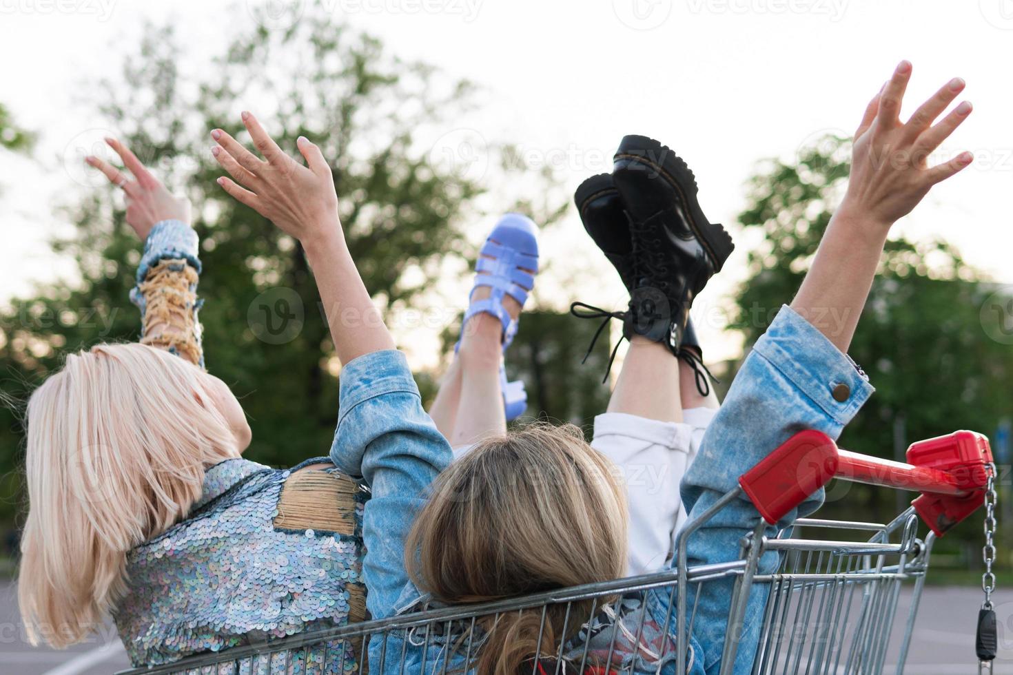 Two young happy girls sitting in a shopping trolley photo