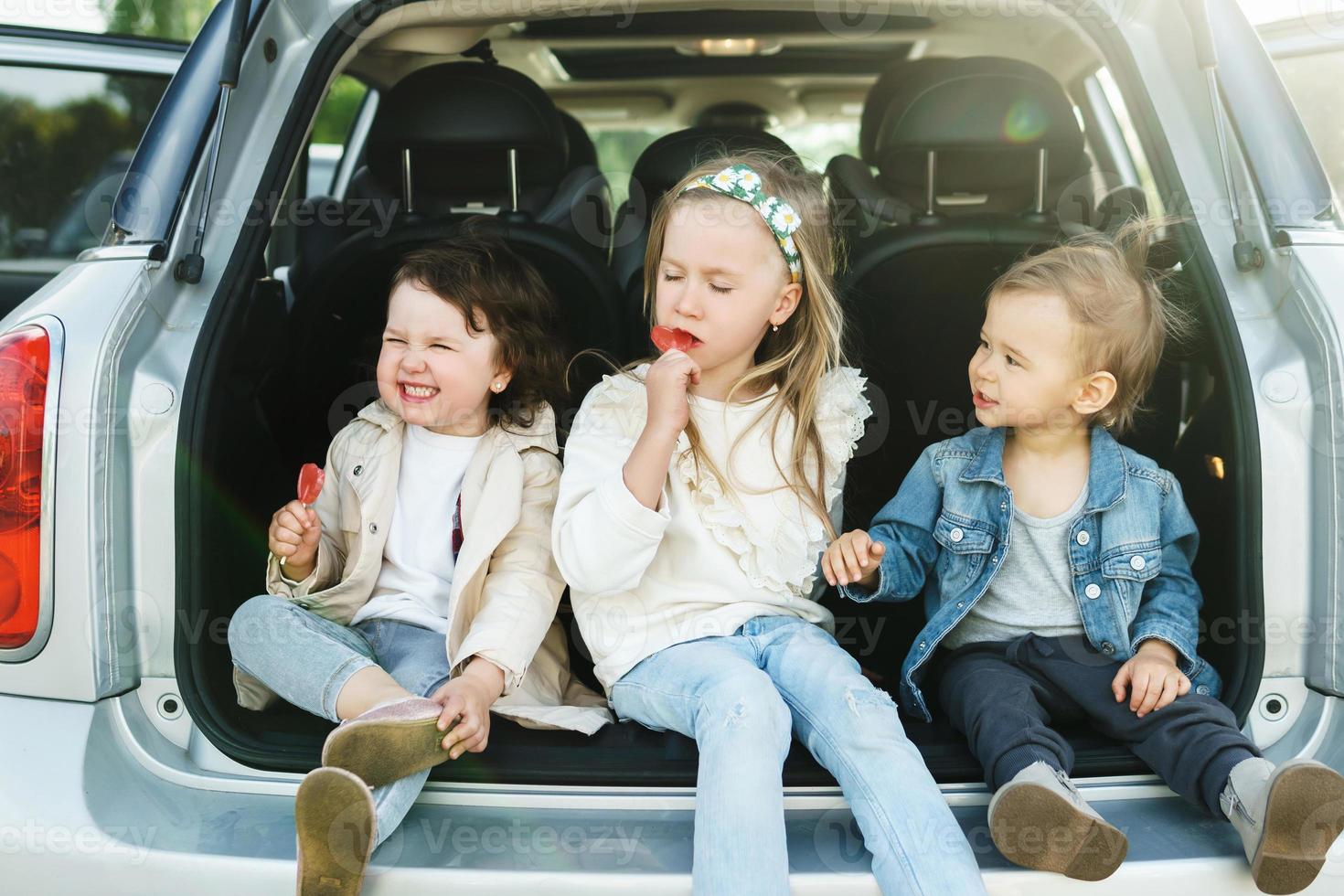 Little kids sitting in a car's trunk before a road trip photo