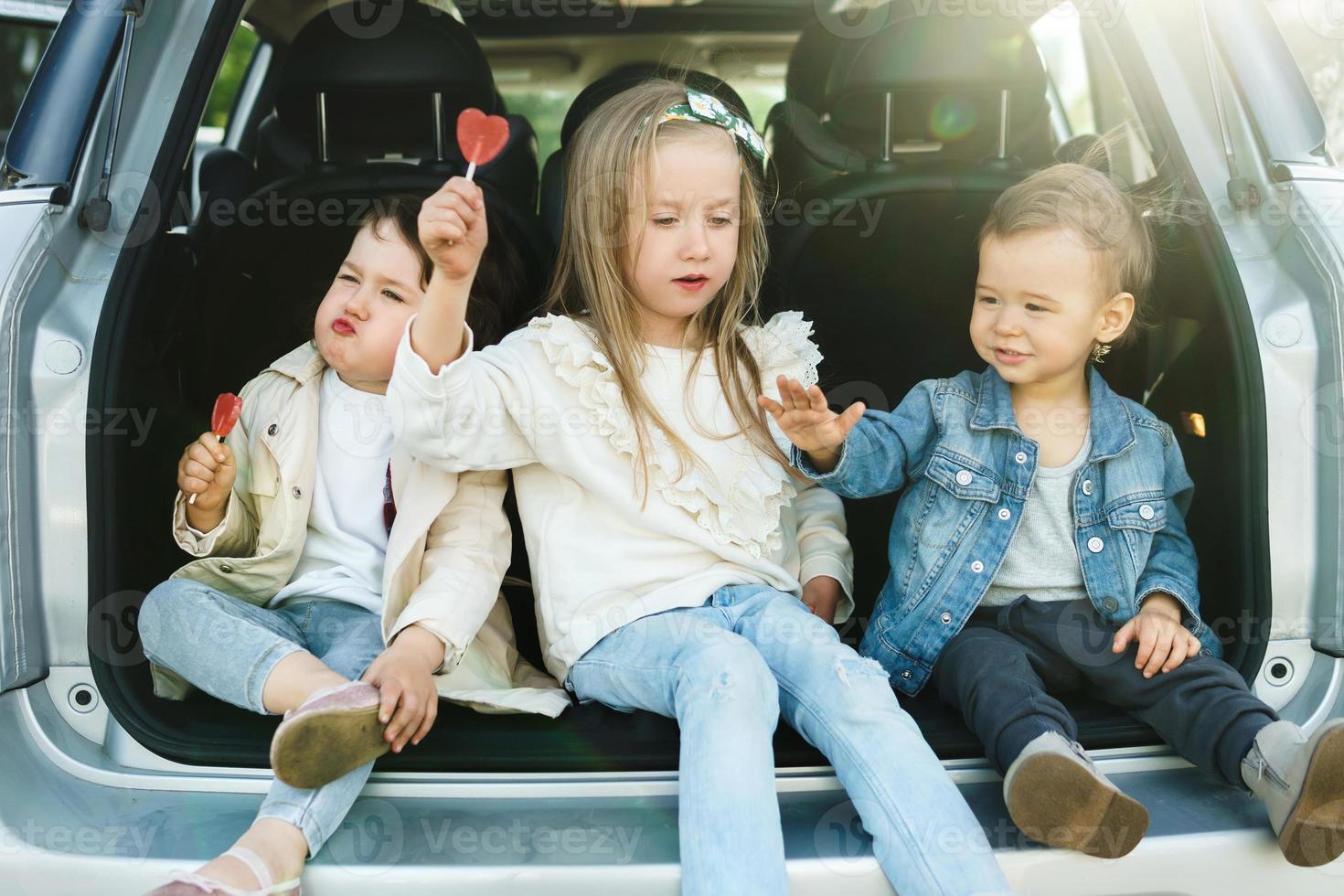 Little kids sitting in a car's trunk before a road trip photo