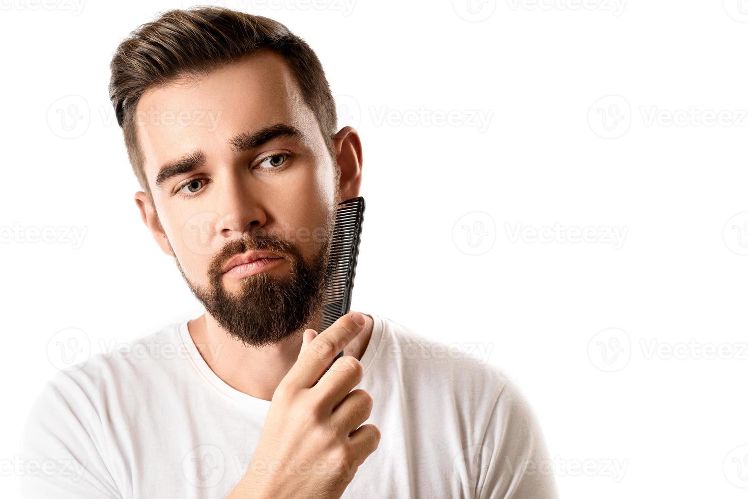 Handsome well groomed man combing his beard photo