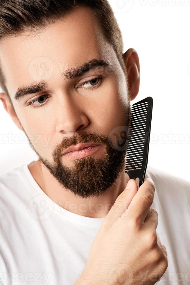 Handsome well groomed man combing his beard photo