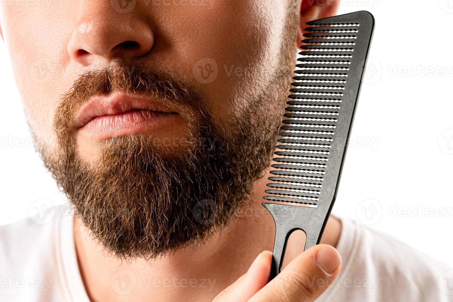 Well groomed man combing his beard photo