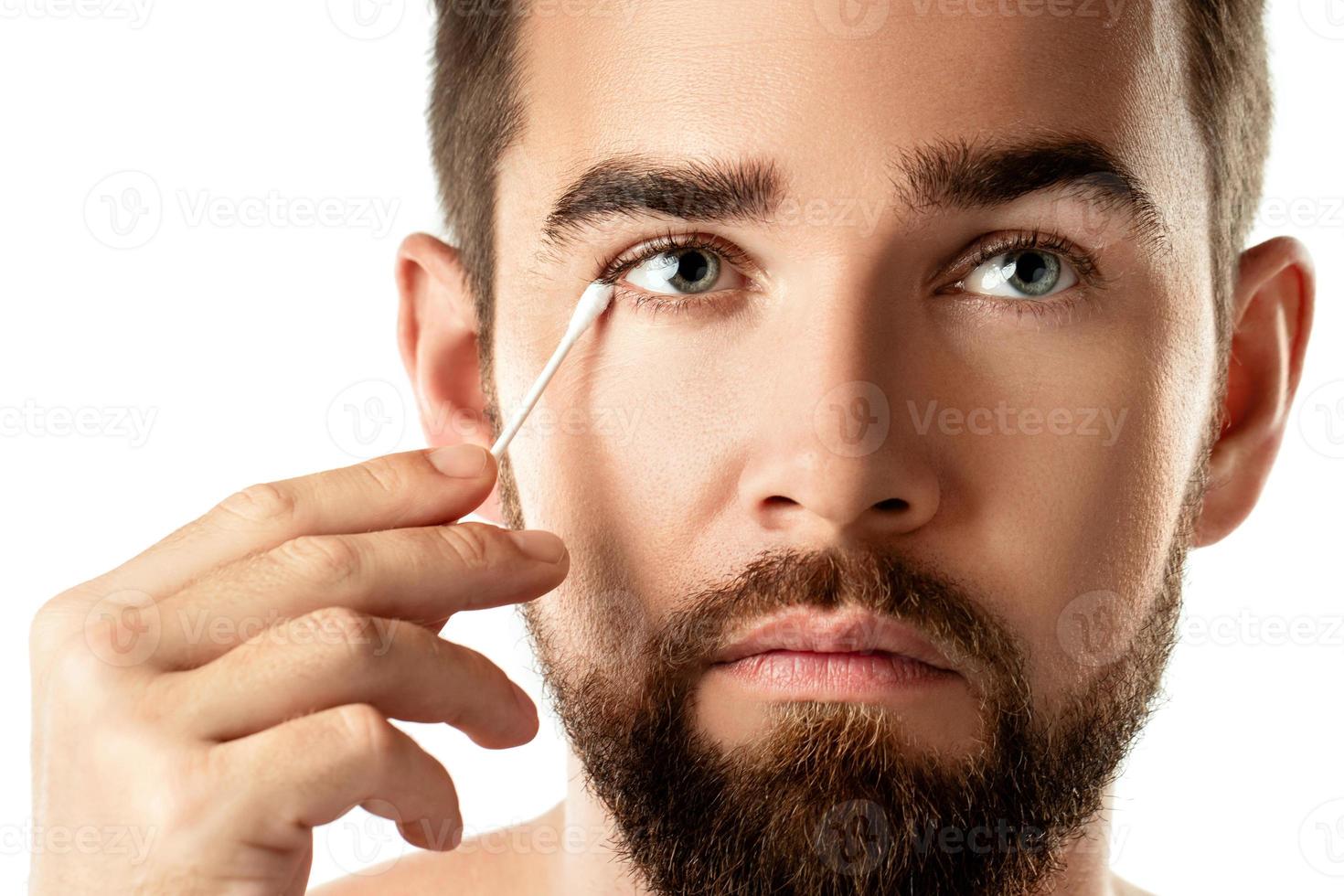 Man cleaning his eye with a cotton swab photo