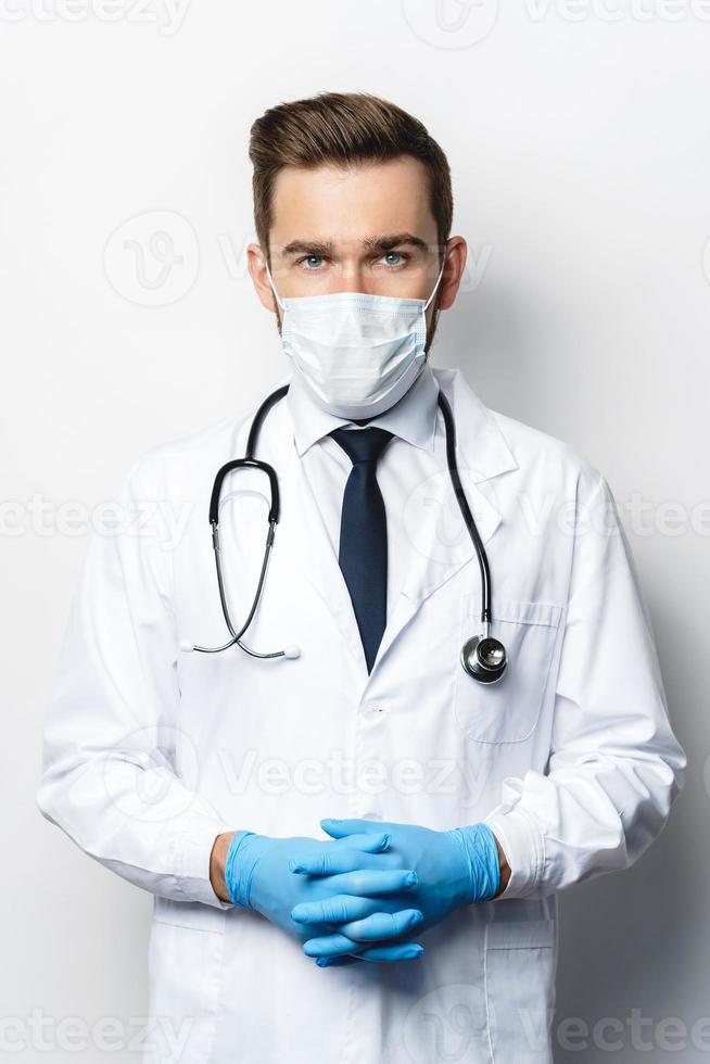 Doctor with the stethoscope wearing prevention mask and latex gloves photo