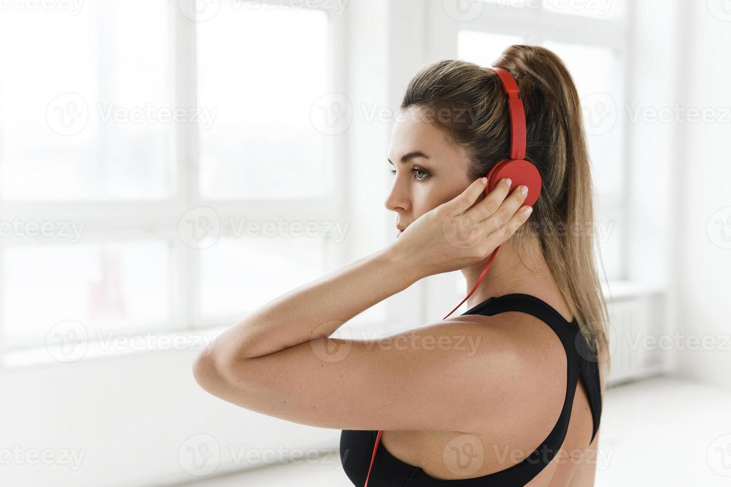 mujer deportiva con auriculares rojos escuchando música para hacer