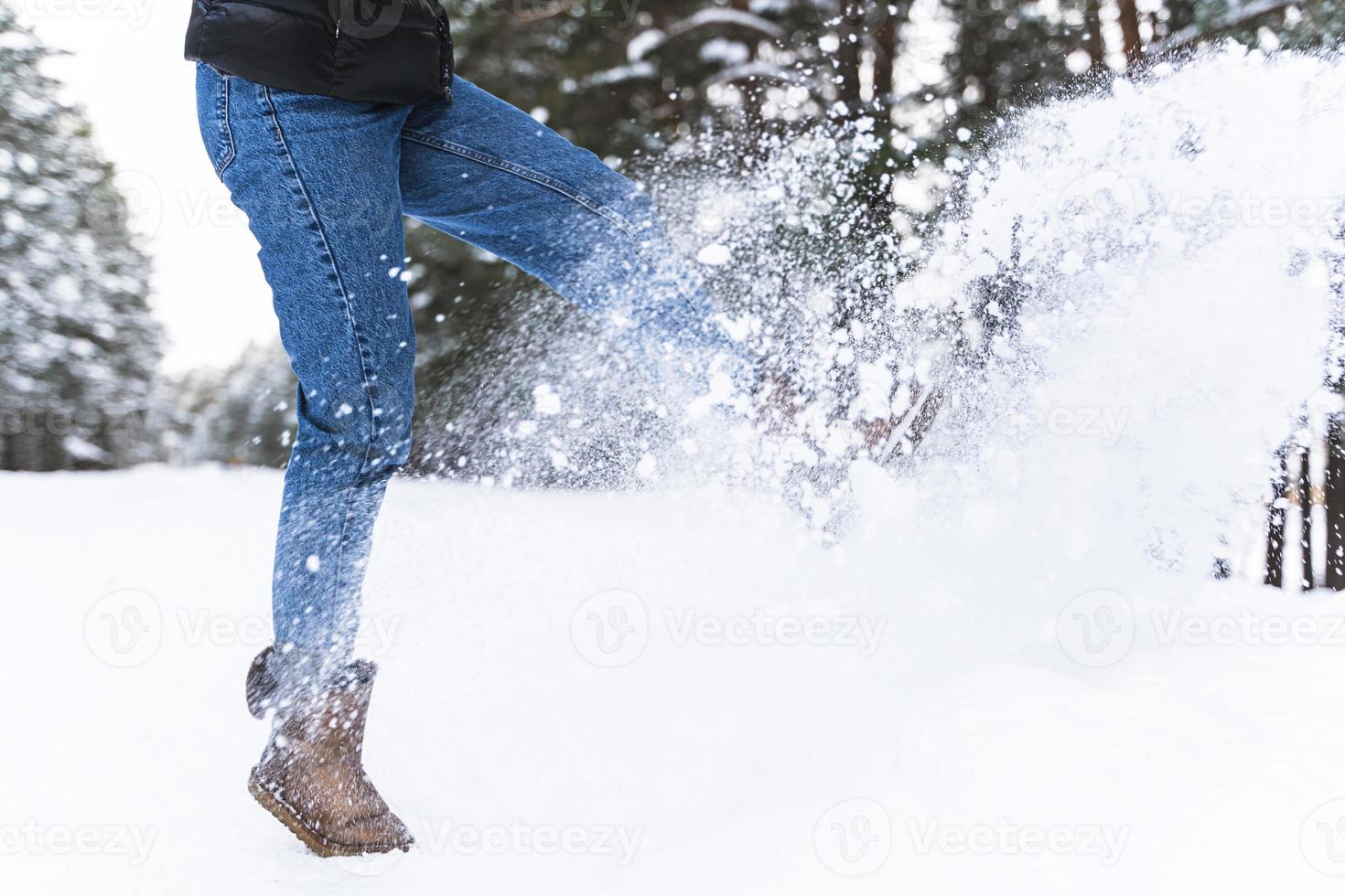 Woman wearing sheepskin boots is kicking snow photo