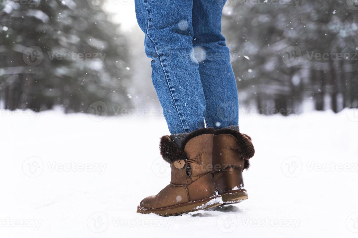 mujer con botas de piel de oveja caminando por un camino nevado foto