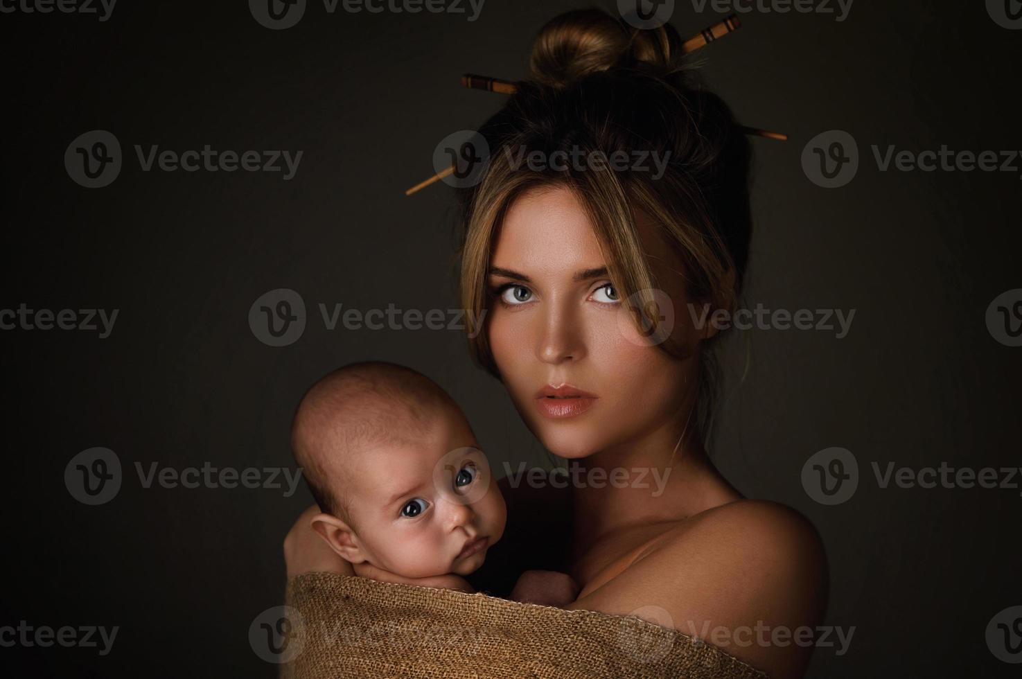hermosa madre y su pequeño bebé están envueltos en tela de saco foto