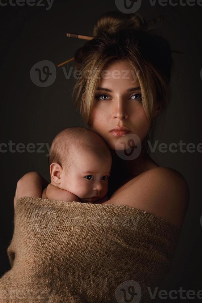 hermosa madre y su pequeño bebé están envueltos en tela de saco foto