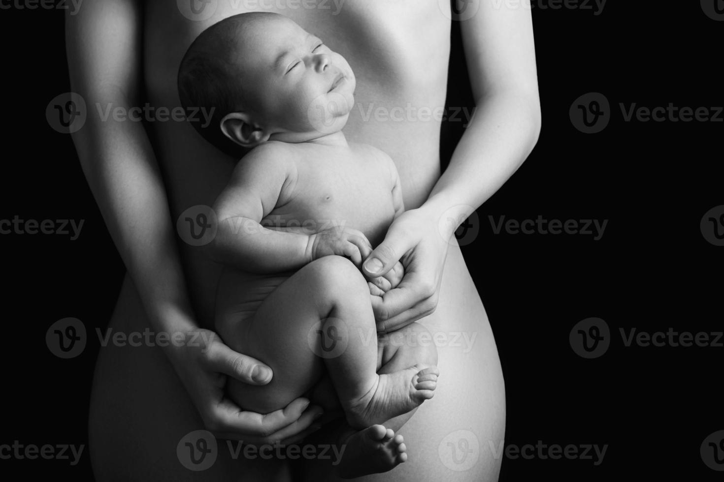 Little newborn baby lying on the mother belly on black background photo