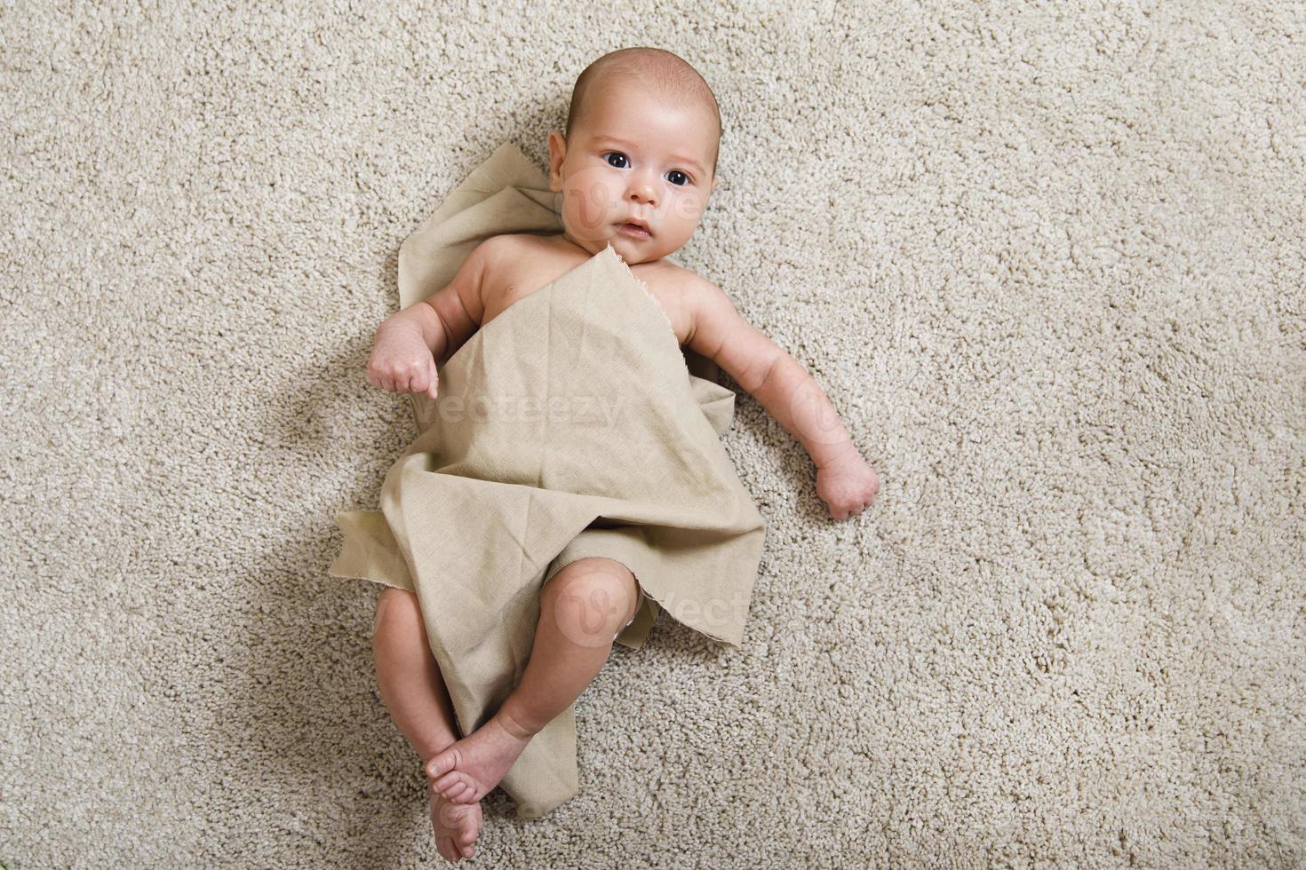 Cute little baby covered with piece of linen fabric photo