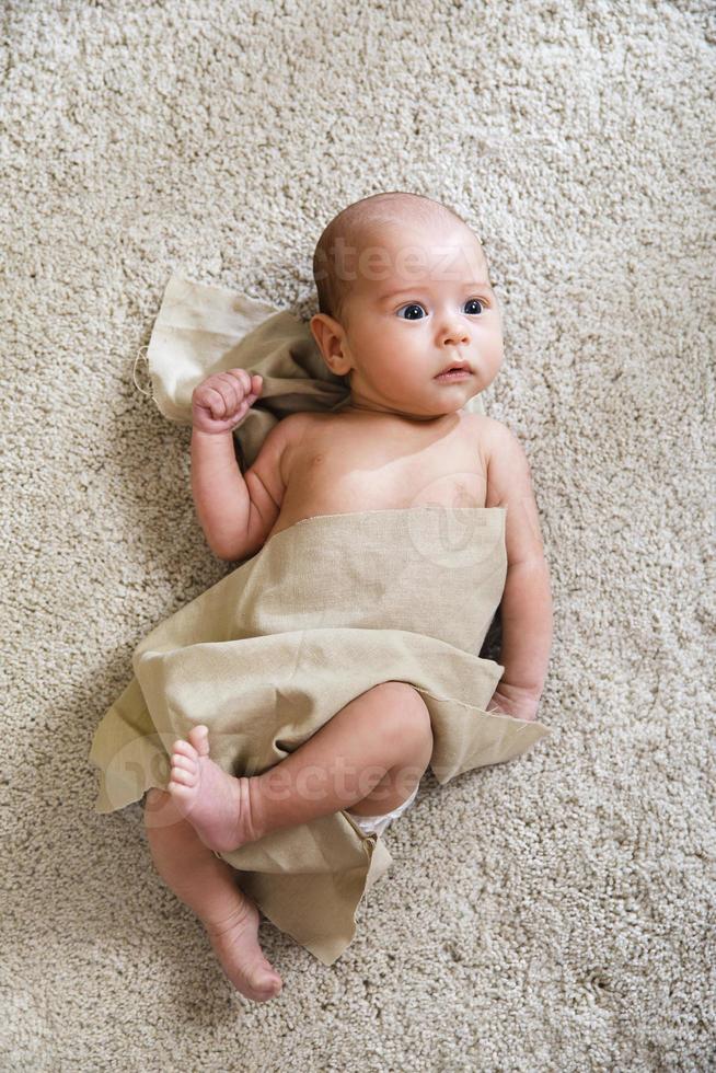 Cute little baby covered with piece of linen fabric photo