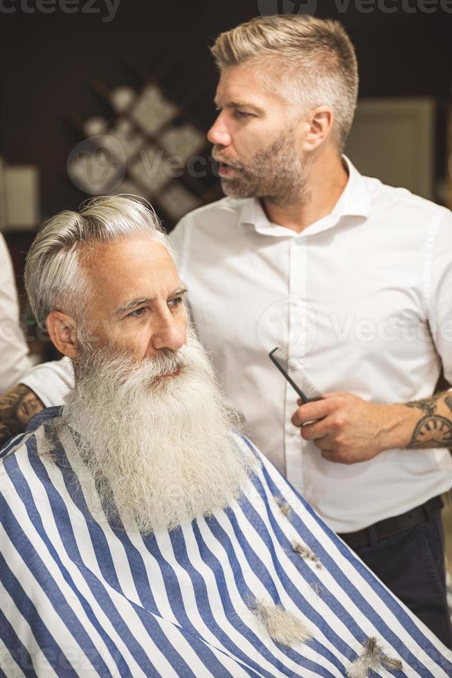 Hairdresser making stylish haircut for a handsome old man photo