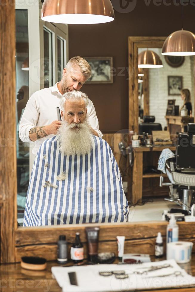 Hairdresser making stylish haircut for a handsome old man photo