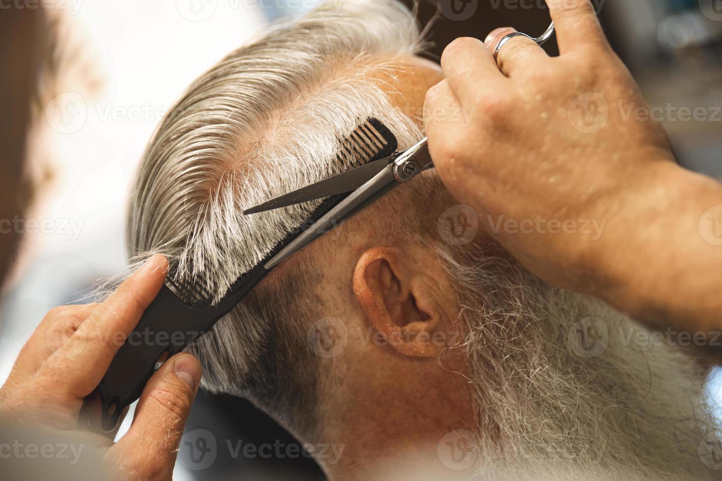 peluquero haciendo un corte de pelo elegante para un anciano foto