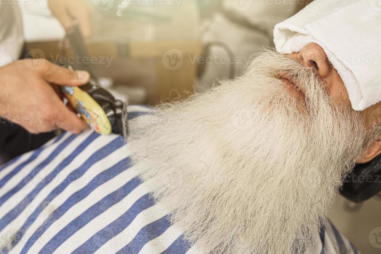 un anciano apuesto que se peina y se corta la barba foto