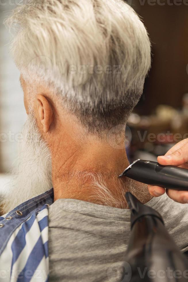 Hairdresser making stylish haircut for old man photo