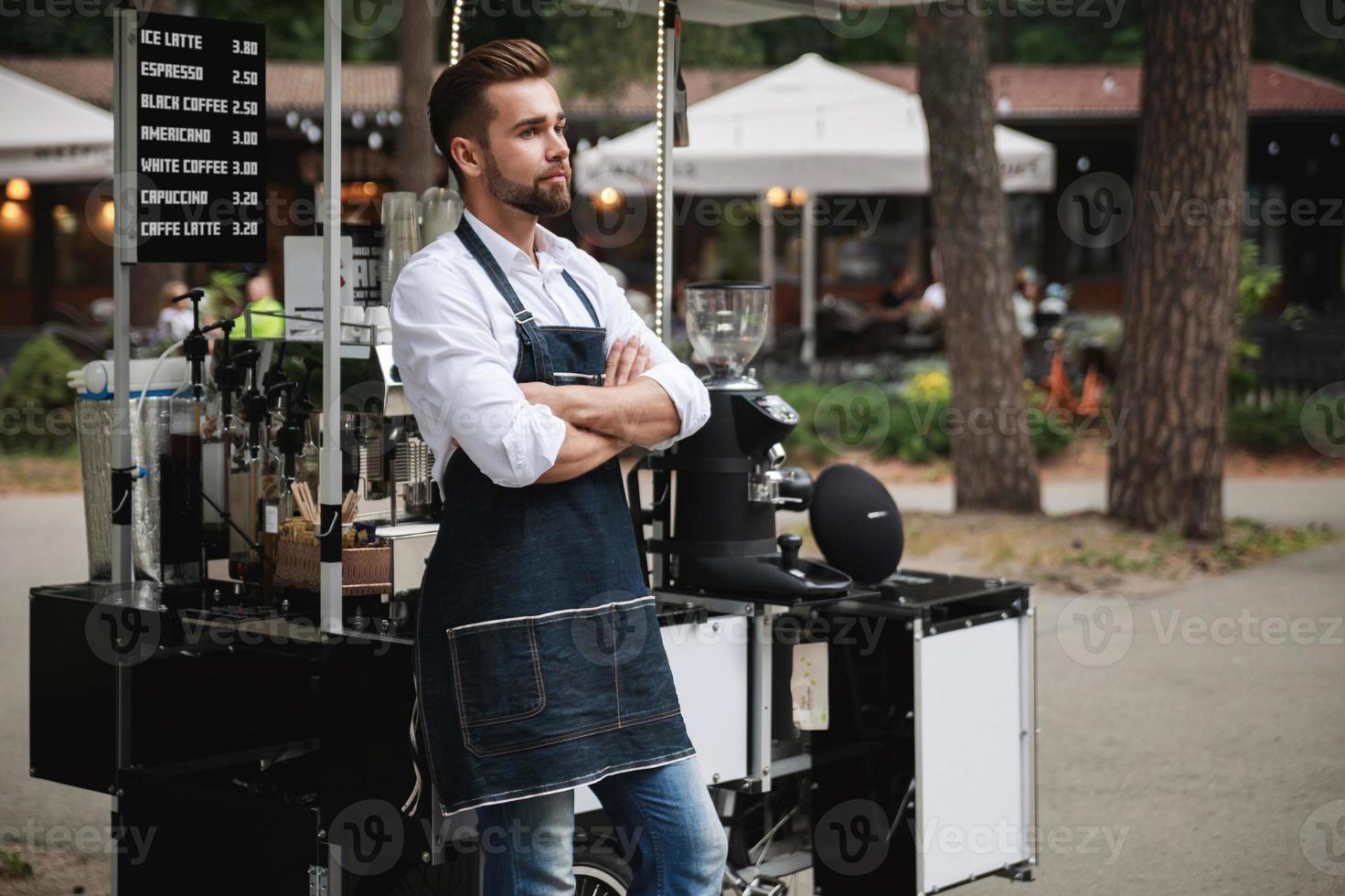Handsome barista man during work in his street coffee shop photo