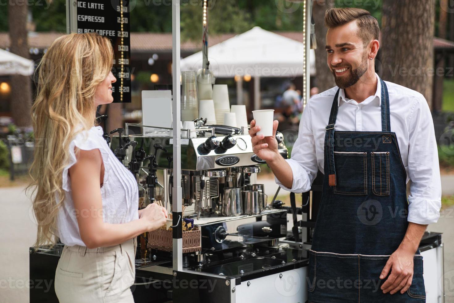 Barista man giving cup of coffee to woman customer photo