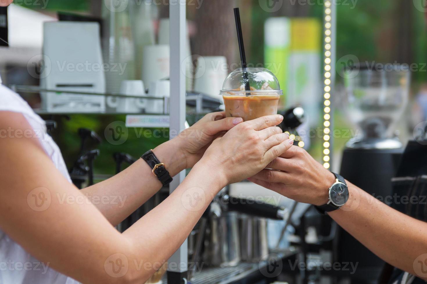 vendedor dando al cliente un vaso de plástico con el café con leche helado foto