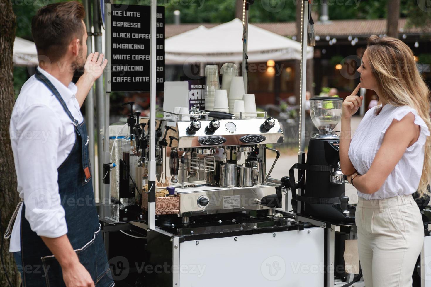 Barista man offer to choose various kinds of coffee to the woman customer photo